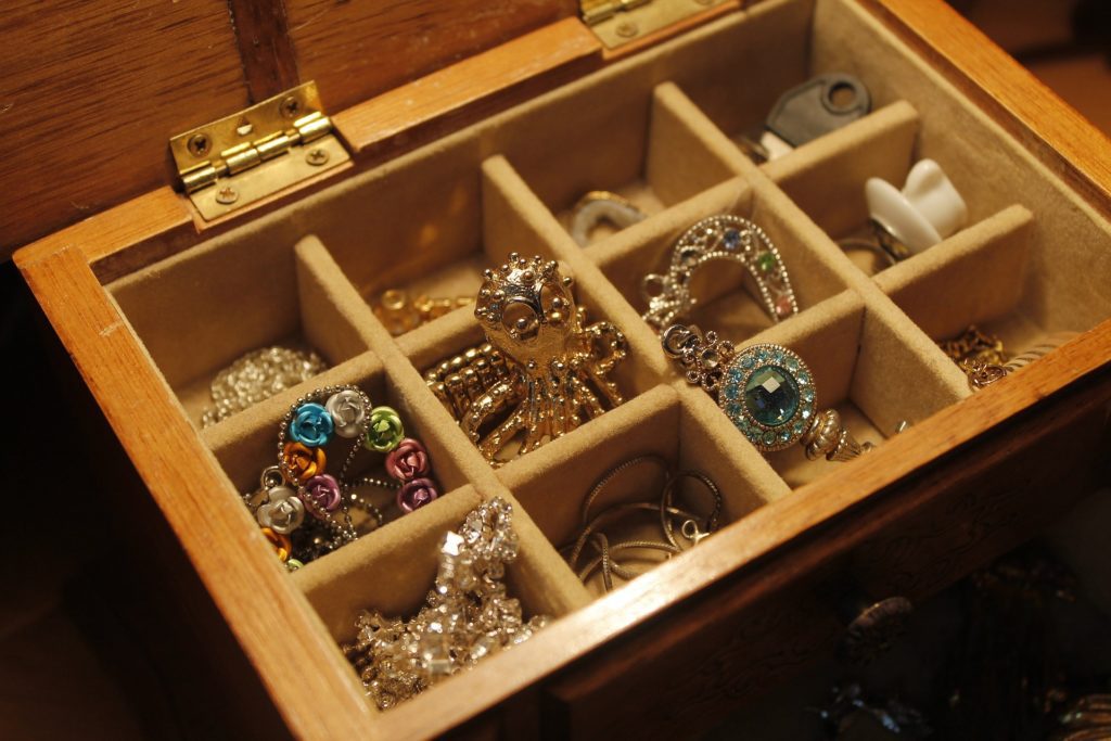 A wooden box filled with a variety of jewelry.